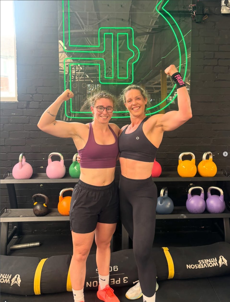 Lesley and a client flexing in the gym